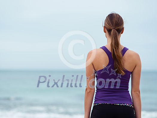 Sporty young woman standing on the sea coast Sporty young woman standing on the sea coast