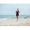 Sporty young woman running on the sea coast
