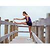 Sporty young woman stretching on the sea coast