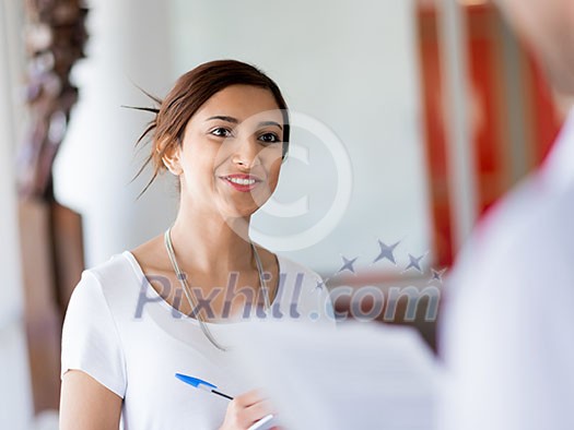 Young business woman talking to her collegue and smiling Young business woman talking to her collegue and smiling