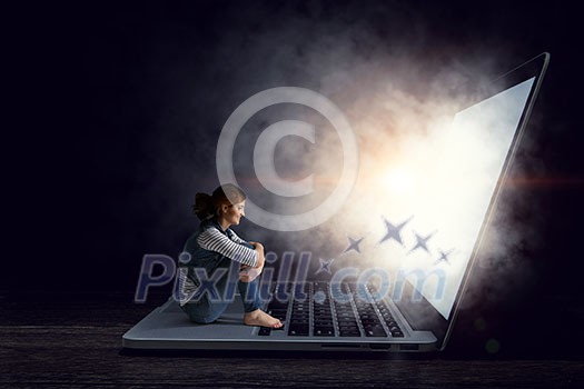 Young sad woman sitting on big laptop. Mixed media Young sad woman sitting on big laptop. Mixed media