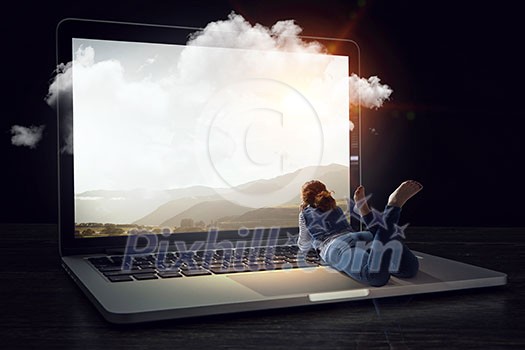 Young woman lying on big laptop. Mixed media Young woman lying on big laptop. Mixed media