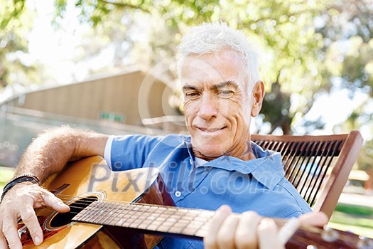 Handsome senior man playing guitar in summer park Handsome senior man playing guitar in summer park