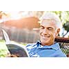 Handsome senior sitting in park and reading book
