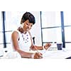 Young beautiful woman sitting at a desk in an office and working on blueprint