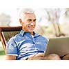 Handsome senior man with notebook sitting in the park