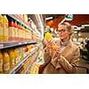 Pretty, young woman shopping for her favorite fruit juice/smoothie at a grocery store