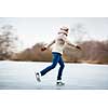 Young woman ice skating outdoors on a pond on a freezing winter day