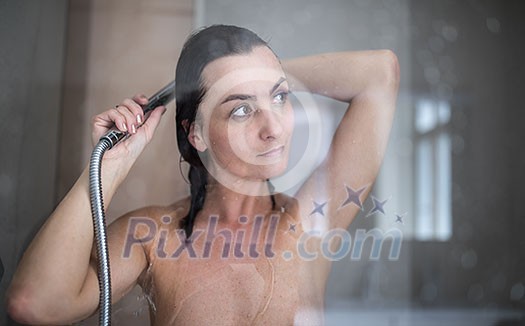 Woman taking a long hot shower washing her hair in a modern design bathroom Woman taking a long hot shower washing her hair in a modern design bathroom
