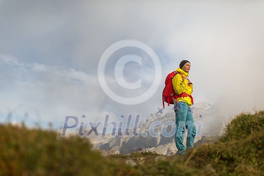 Pretty, young female hiker walking in high mountains (shallow DOF) Pretty, young female hiker walking in high mountains (shallow DOF)