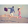 couple on beach with travel bag representing freedom and funy honeymoon concept