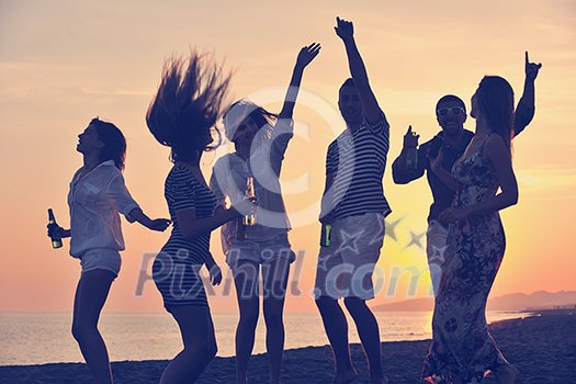 Group of young people enjoy summer party at the beach on beautiful sunset Group of young people enjoy summer party at the beach on beautiful sunset