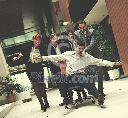 business people group at modern office indoors have fun and push office chair on corridor business people group at modern office indoors have fun and push office chair on corridor