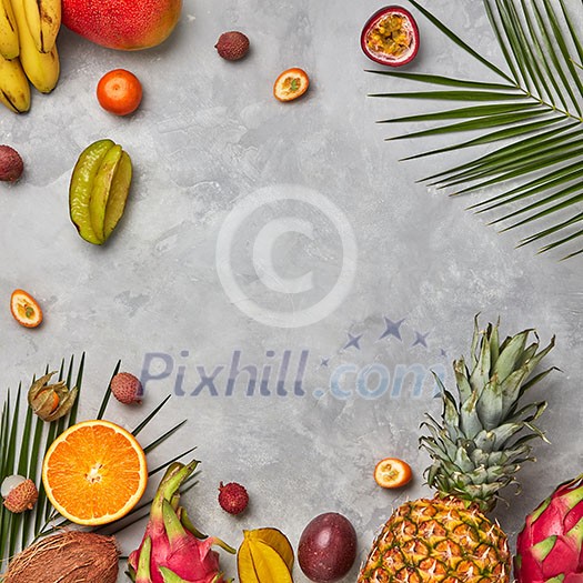 Various juicy exotic fruits, coconut, lychee, carom, pineapple and palm leaves on a gray concrete background with space for text. Food layout. Flat lay Various juicy exotic fruits, coconut, lychee, carom, pineapple and palm leaves on a gray concrete background with space for text. Food layout. Flat lay