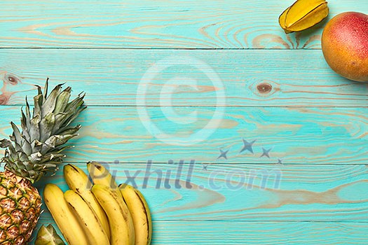 Corner frame of tropical fruits, banana, mango, carambola and pineapple on a blue wooden background with copy space. Flat lay Corner frame of tropical fruits, banana, mango, carambola and pineapple on a blue wooden background with copy space. Flat lay