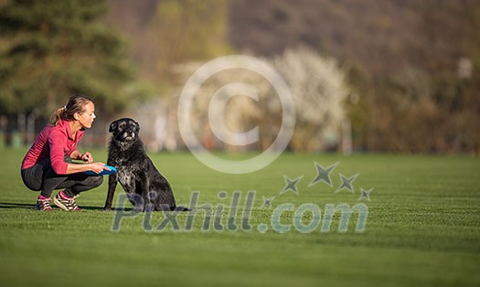 Young woman with her black dog outdoor, in a park playing frisbee - shallow DOF, sharp focus Young woman with her black dog outdoor, in a park playing frisbee - shallow DOF, sharp focus
