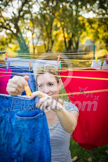 Young woman putting laundry on a rope in her garden, taking great care of her family on a daily basis Young woman putting laundry on a rope in her garden, taking great care of her family on a daily basis