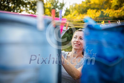 Young woman putting laundry on a rope in her garden, taking great care of her family on a daily basis Young woman putting laundry on a rope in her garden, taking great care of her family on a daily basis