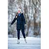 Young woman ice skating outdoors on a pond on a freezing winter day