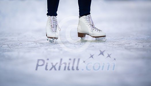 Young woman ice skating outdoors on a pond on a freezing winter day - detail of the skates