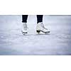 Young woman ice skating outdoors on a pond on a freezing winter day - detail of the skates