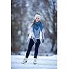 Young woman ice skating outdoors on a pond on a freezing winter day