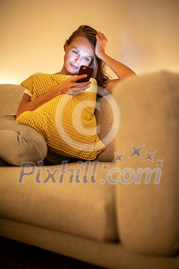 Cute young woman on a comfortable sofa in her modern apartment using her cell phone Cute young woman on a comfortable sofa in her modern apartment using her cell phone