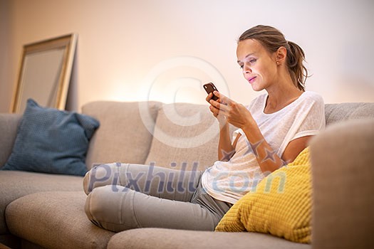 Cute young woman on a comfortable sofa in her modern apartment using her cell phone Cute young woman on a comfortable sofa in her modern apartment using her cell phone