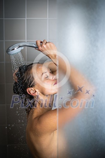 Woman taking a long hot shower washing her hair in a modern design bathroom Woman taking a long hot shower washing her hair in a modern design bathroom