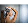 Woman taking a long hot shower washing her hair in a modern design bathroom