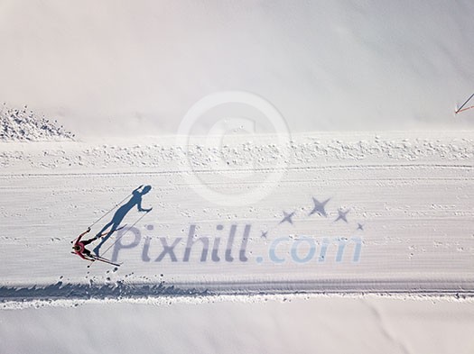 Cross-country skiing: young woman cross-country skiing on a winter day (motion blurred image) - aerial image Cross-country skiing: young woman cross-country skiing on a winter day (motion blurred image) - aerial image