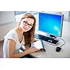 Smiling female student/ businesswoman using her tablet computer and a desktop computer, staying up to date, working, looking at the camera.