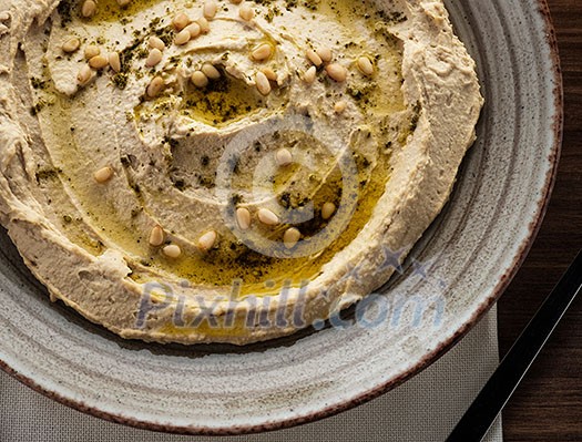 Delicious hummus with pine nuts and olive oil. Top view. Close-up. Delicious hummus with pine nuts and olive oil. Top view. Close-up.