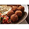 Close-up of Traditional falafel balls with salad and hummus on a plate.