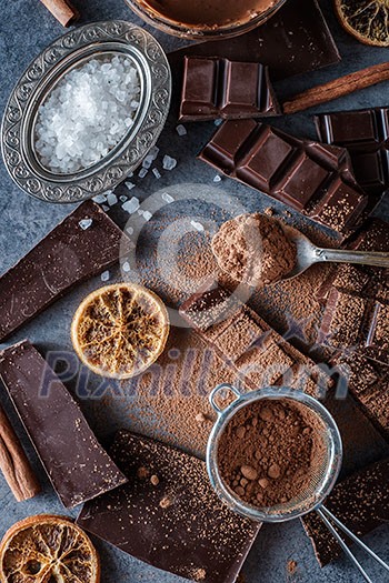 Dark chocolate bars with dry orange slices, cinnamon sticks and salt on blue background Dark chocolate bars with dry orange slices, cinnamon sticks and salt on blue background