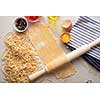 Homemade pasta dough is being processed. Rolled dough for homemade italian uncooked pasta over white marble texture background. 