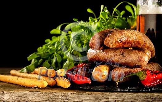Grilled sausages with a glass of beer on a wooden table. Rustic style. Snacks for the Oktoberfest. Grilled sausages with a glass of beer on a wooden table. Rustic style. Snacks for the Oktoberfest.