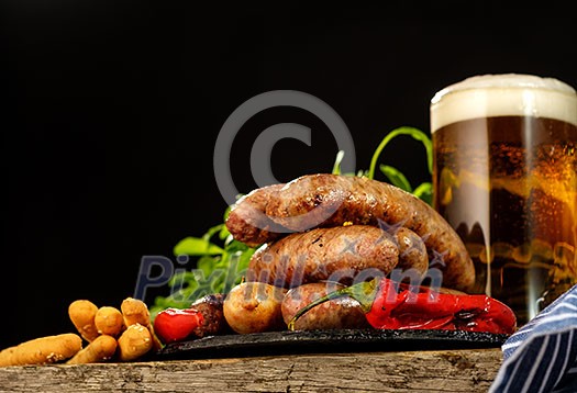 Grilled sausages with a glass of beer on a wooden table. Rustic style. Snacks for the Oktoberfest. Grilled sausages with a glass of beer on a wooden table. Rustic style. Snacks for the Oktoberfest.