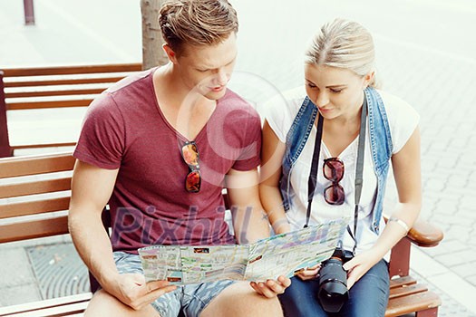 Happy young couple as tourists with a map Happy young couple as tourists with a map