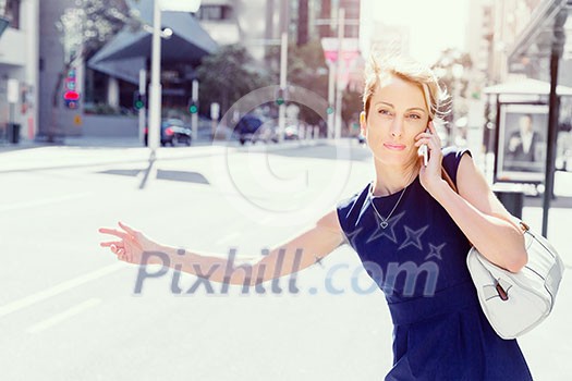Businesswoman in a city street waving for taxi Businesswoman in a city street waving for taxi