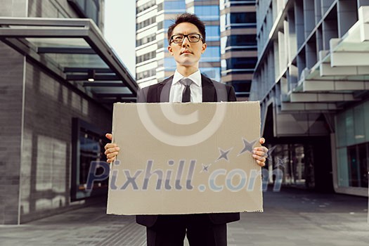 Businessman in a city street holding a blank banner Businessman in a city street holding a blank banner