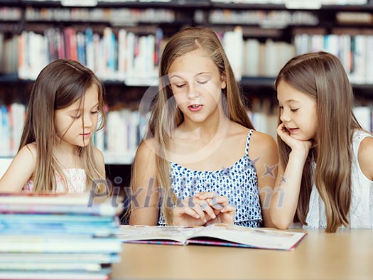 Little girls reading books in library Little girls reading books in library