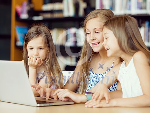 Little girls with a laptop in library Little girls with a laptop in library