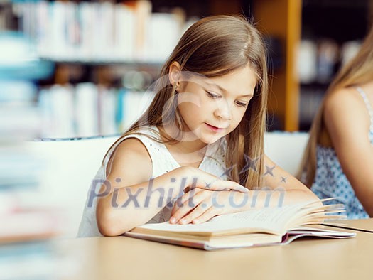 Little girl reading books in library Little girl reading books in library