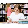 Teenage girl with books studying in library