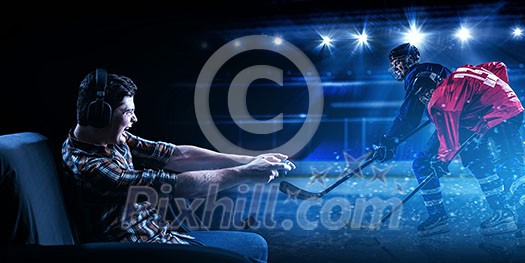 Man sitting on sofa and playing hockey game with joystick. Mixed media Man sitting on sofa and playing hockey game with joystick. Mixed media