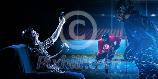 Man sitting on sofa and playing hockey game with joystick. Mixed media Man sitting on sofa and playing hockey game with joystick. Mixed media