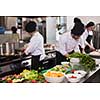 Professional team cooks and chefs preparing meals at busy hotel or restaurant  kitchen