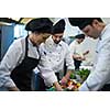 Professional team cooks and chefs preparing meals at busy hotel or restaurant  kitchen