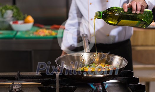 Young male chef flipping vegetables in wok at commercial kitchen Young male chef flipping vegetables in wok at commercial kitchen